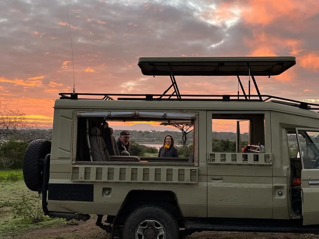 Coucher de soleil romantique en safari avec silhouette de vÃ©hicule en Tanzanie
