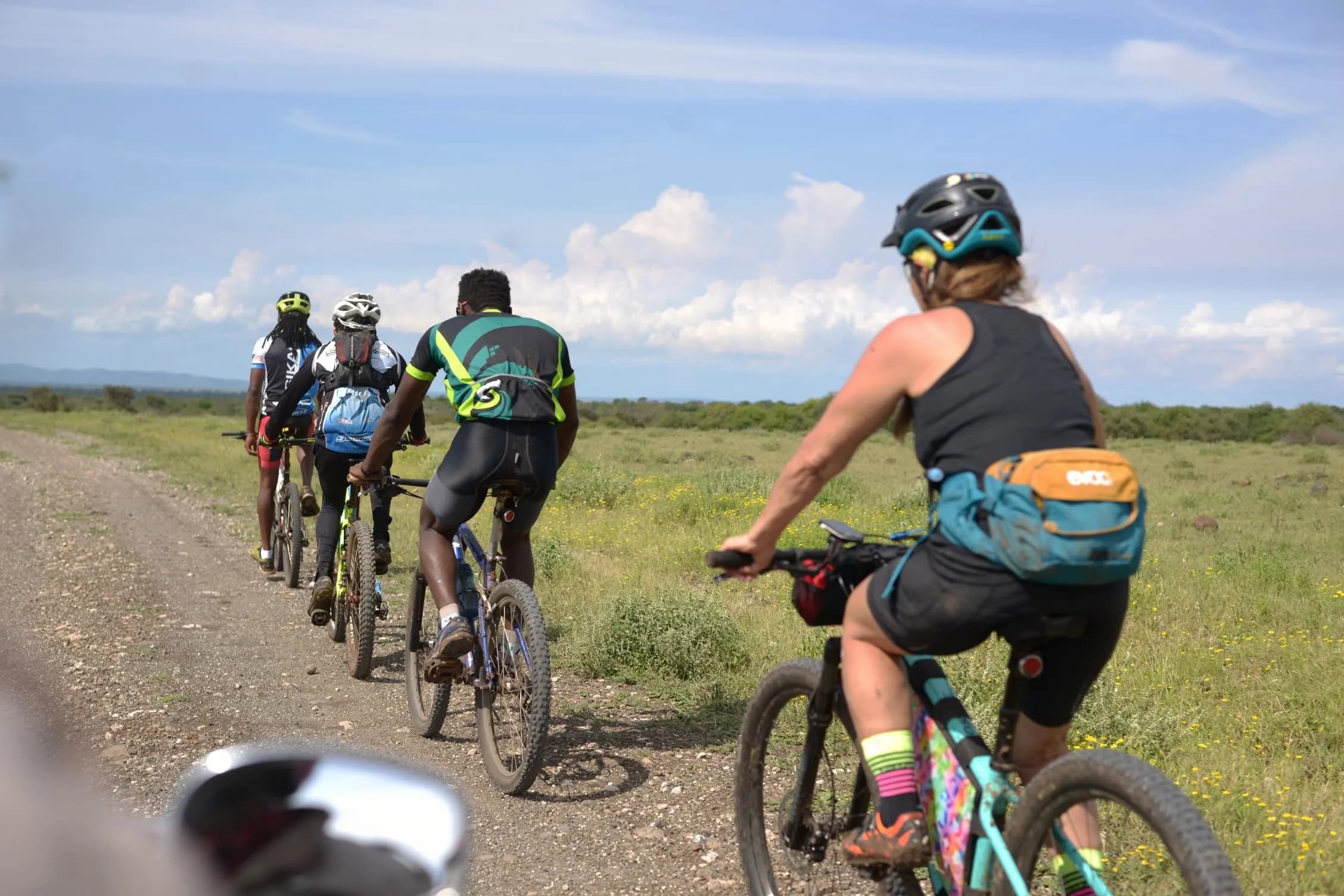 Cyclists on a forest trail in Arusha National Park with tall trees overhead